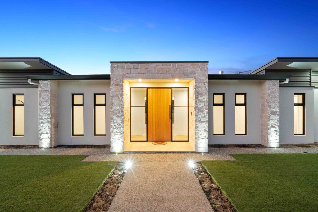 A modern house with a sleek facade, large windows, and a combination of light and dark exterior finishes, built through a knockdown rebuild project.