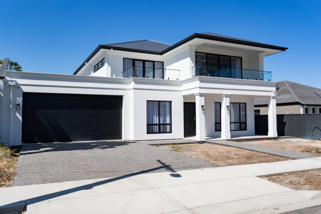 A striking two-story display home in Adelaide by Regent Homes, featuring a bold black-and-white exterior, grand entrance, and expansive balcony.